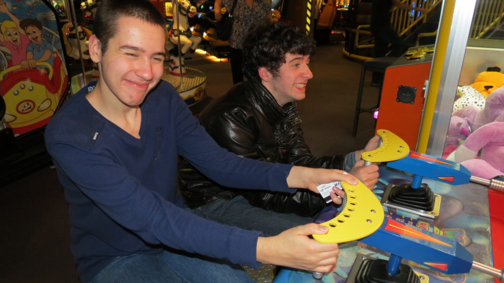 Two young men playing the water gun race arcade game while on a summer camp outing with Camp 625