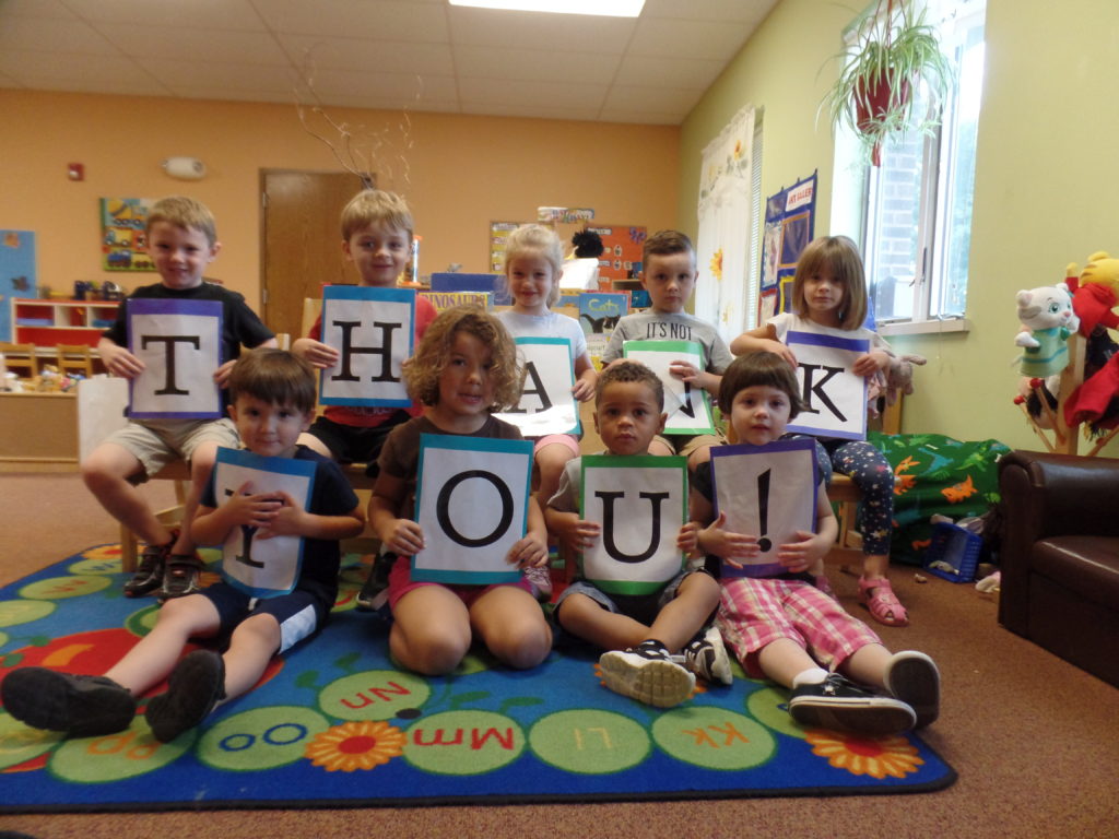 Image shows 9 young children from Schreiber's childcare program each holding a letter to spell out "Thank You!"