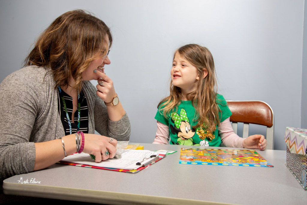 Speech language pathologist works with young girl client on forming the correct letter sounds