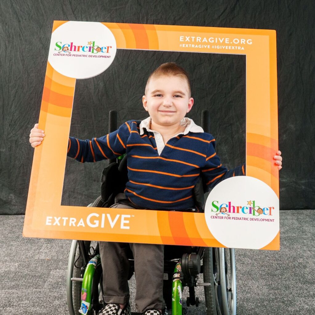 Young boy in wheelchair holding Schreiber's extragive photo sign