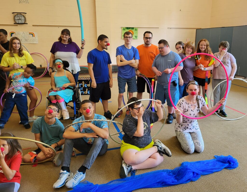 Kids and adults at Camp Schreiber using hula hoops and wearing red noses.