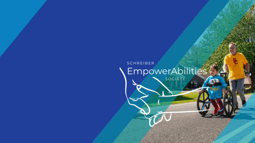 Little boy in stander with dad, alongside the Schreiber EmpowerAbilities Society Logo