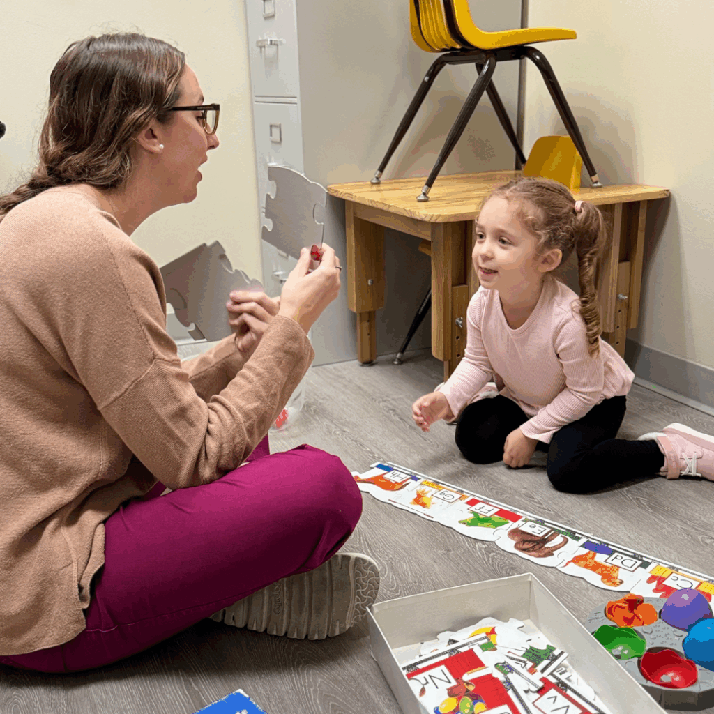 young girl putting together a puzzle with therapist