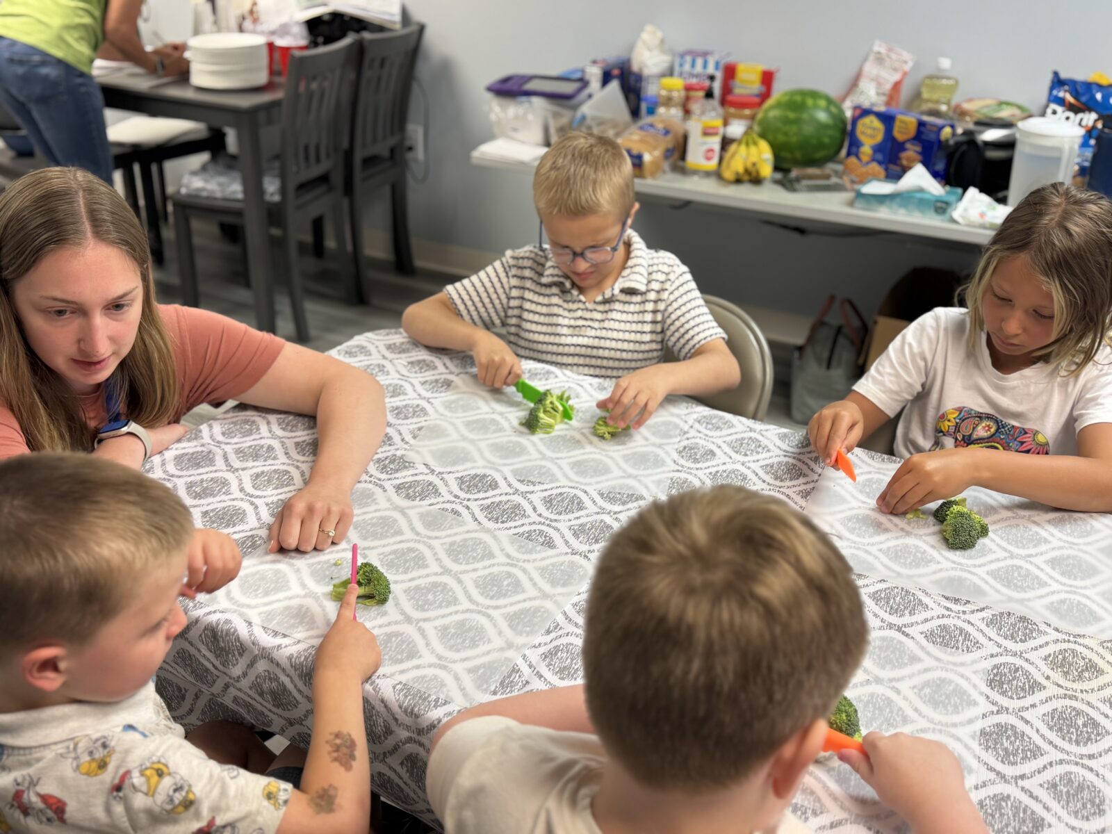 kids at a table cutting broccoli