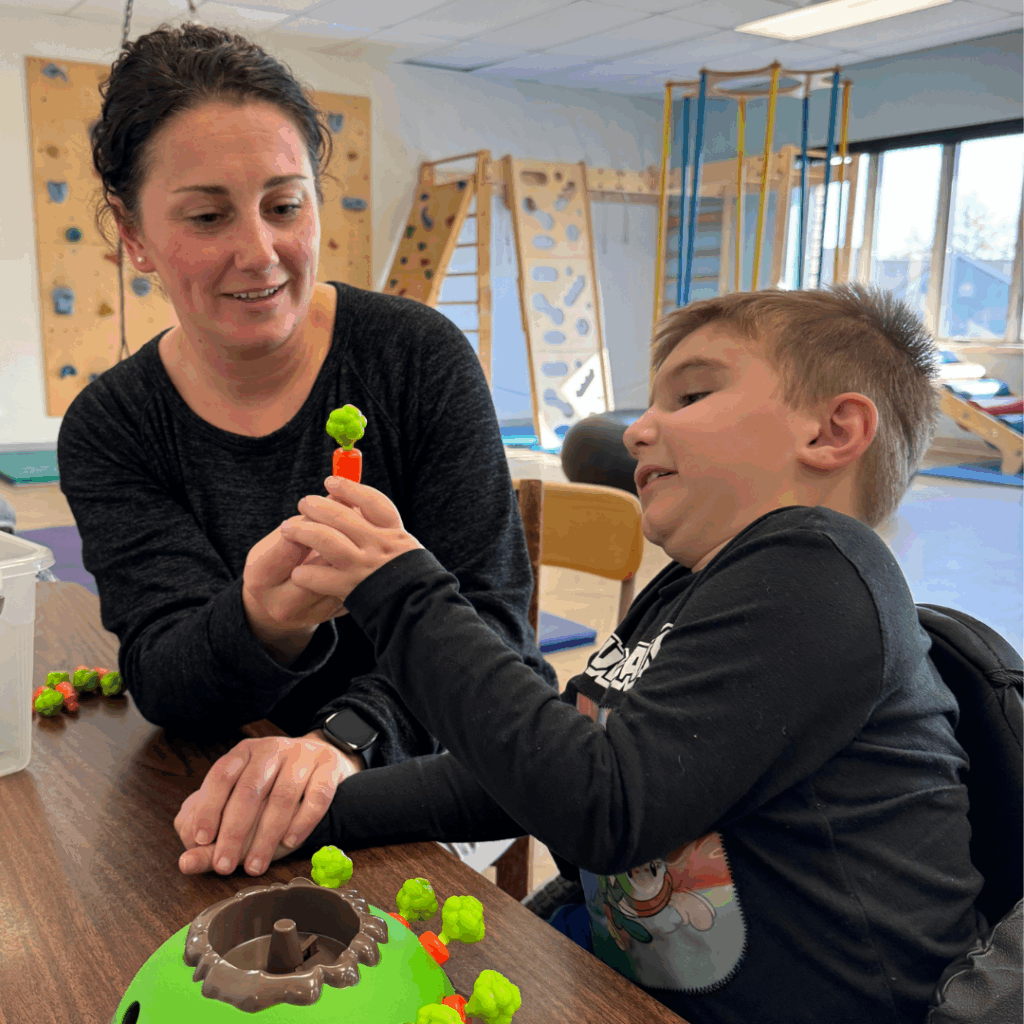 Young boy taking toy from female OT