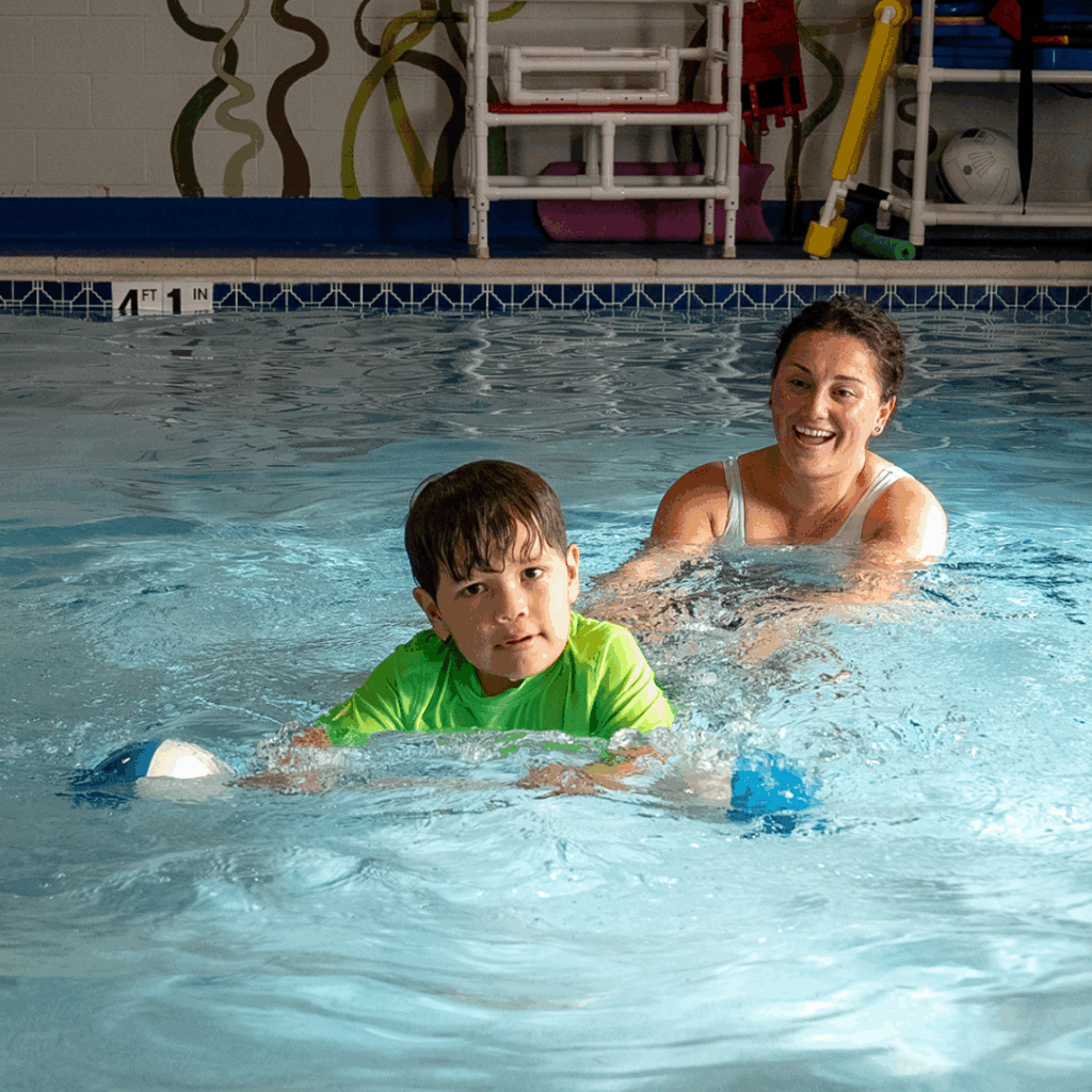Young boy in pool with woman occupational therapist