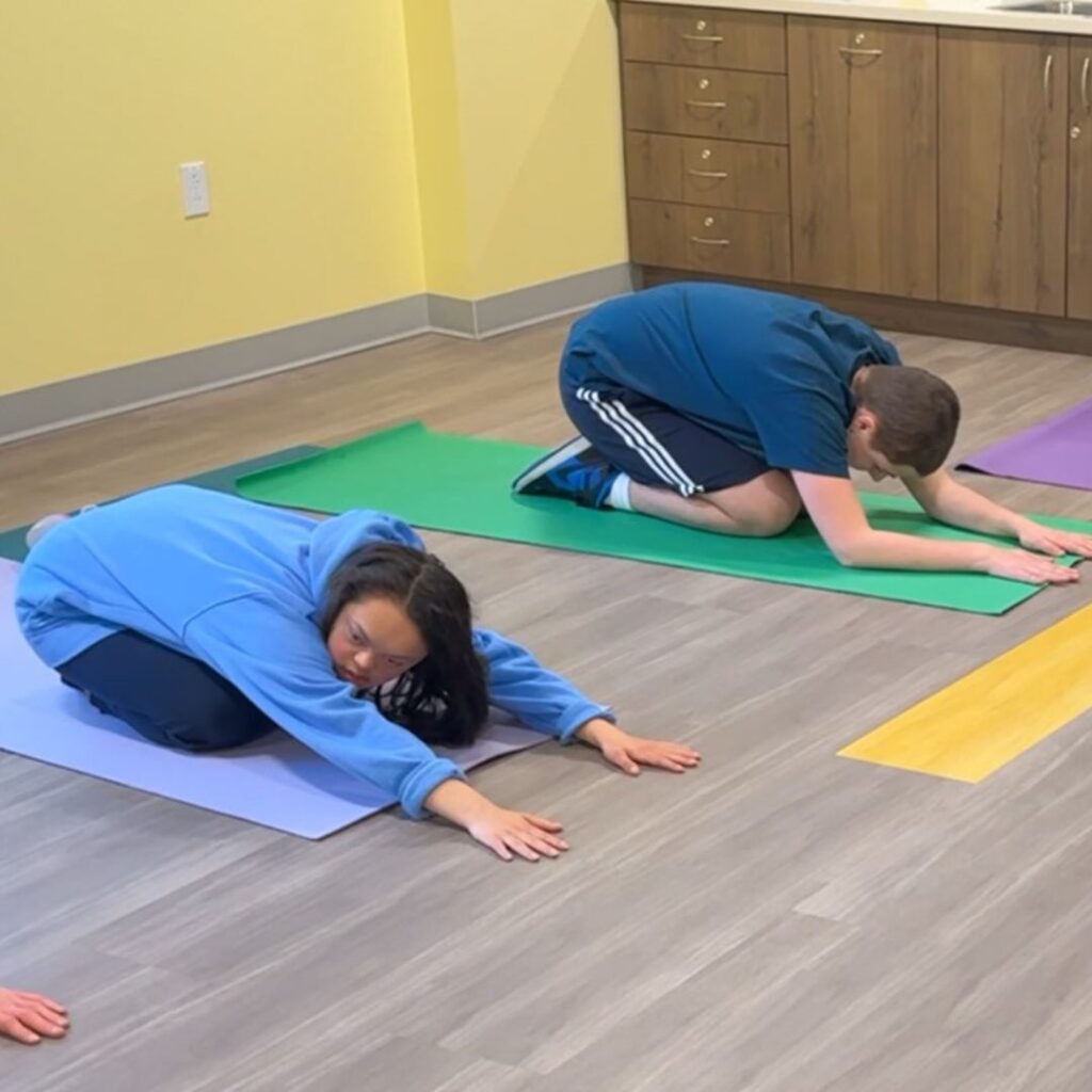 teen girl and teen boy in child's pose on yoga mats