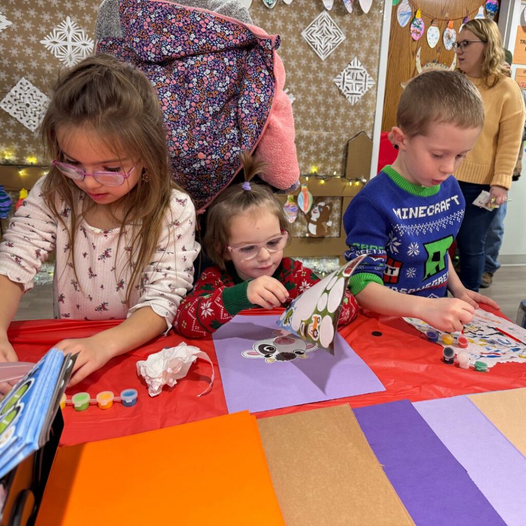 Two little girls and a little boy doing a craft