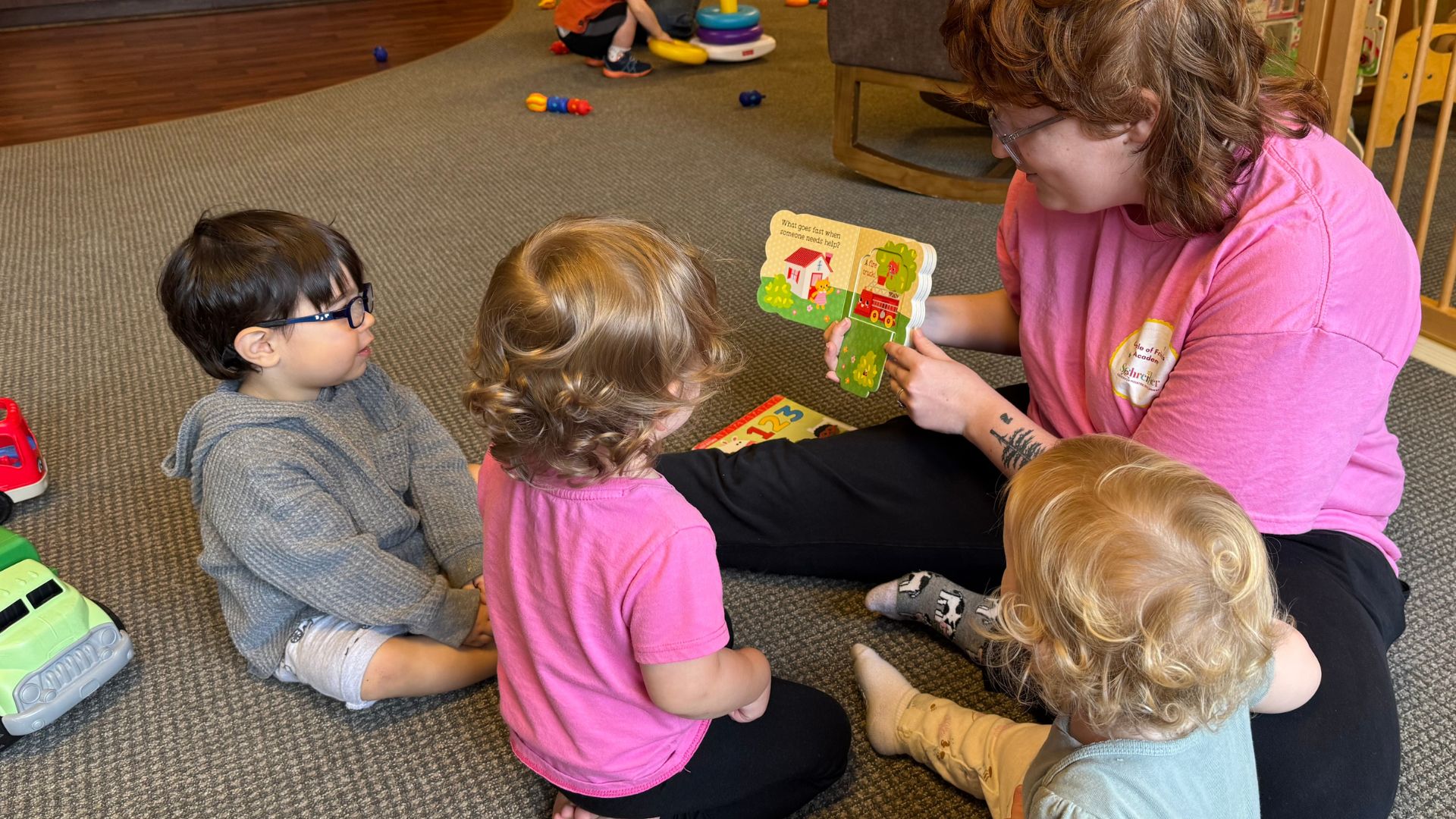 Childcare provider reading to three children in the infant room
