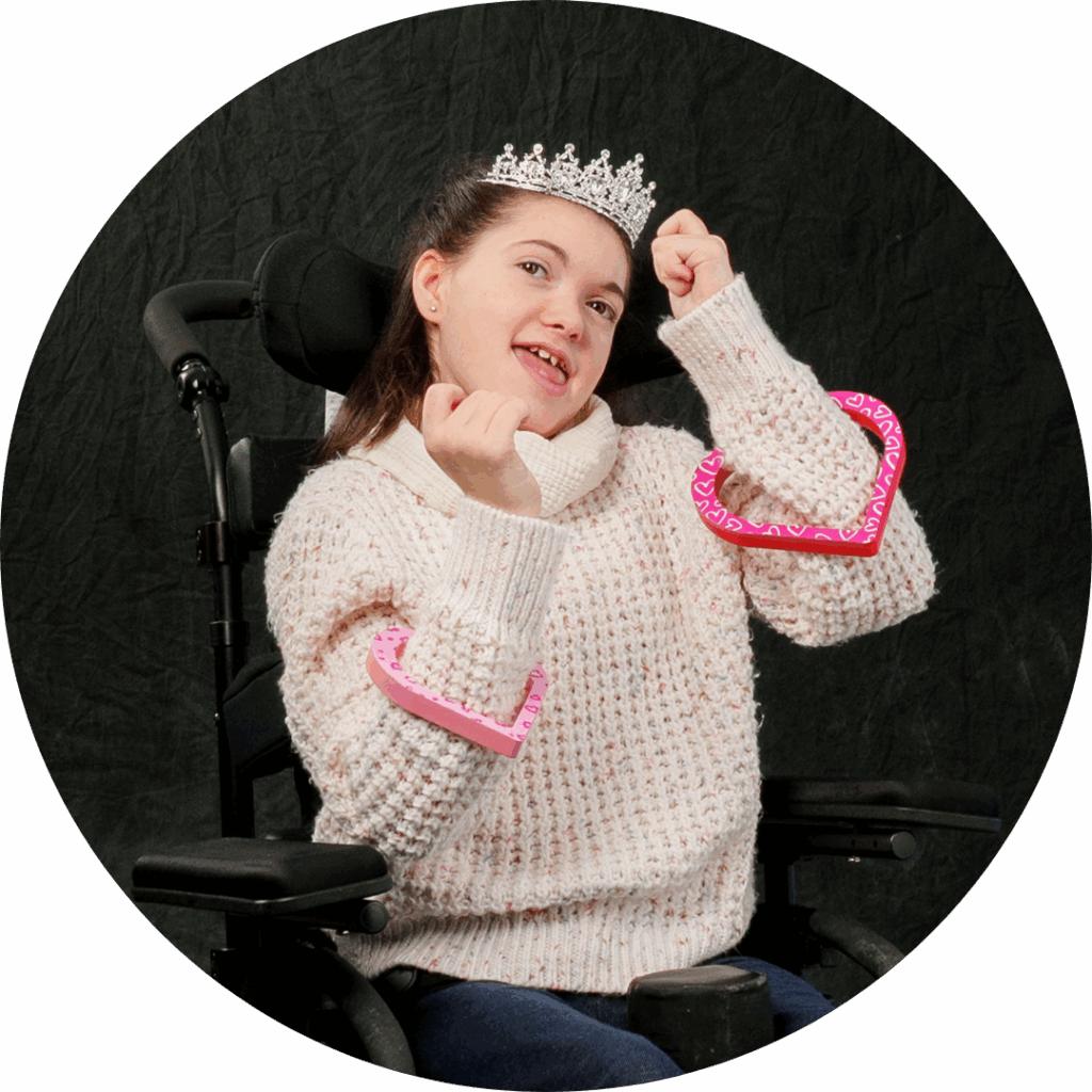 girl in a wheelchair with a tiara on and hearts on her arms