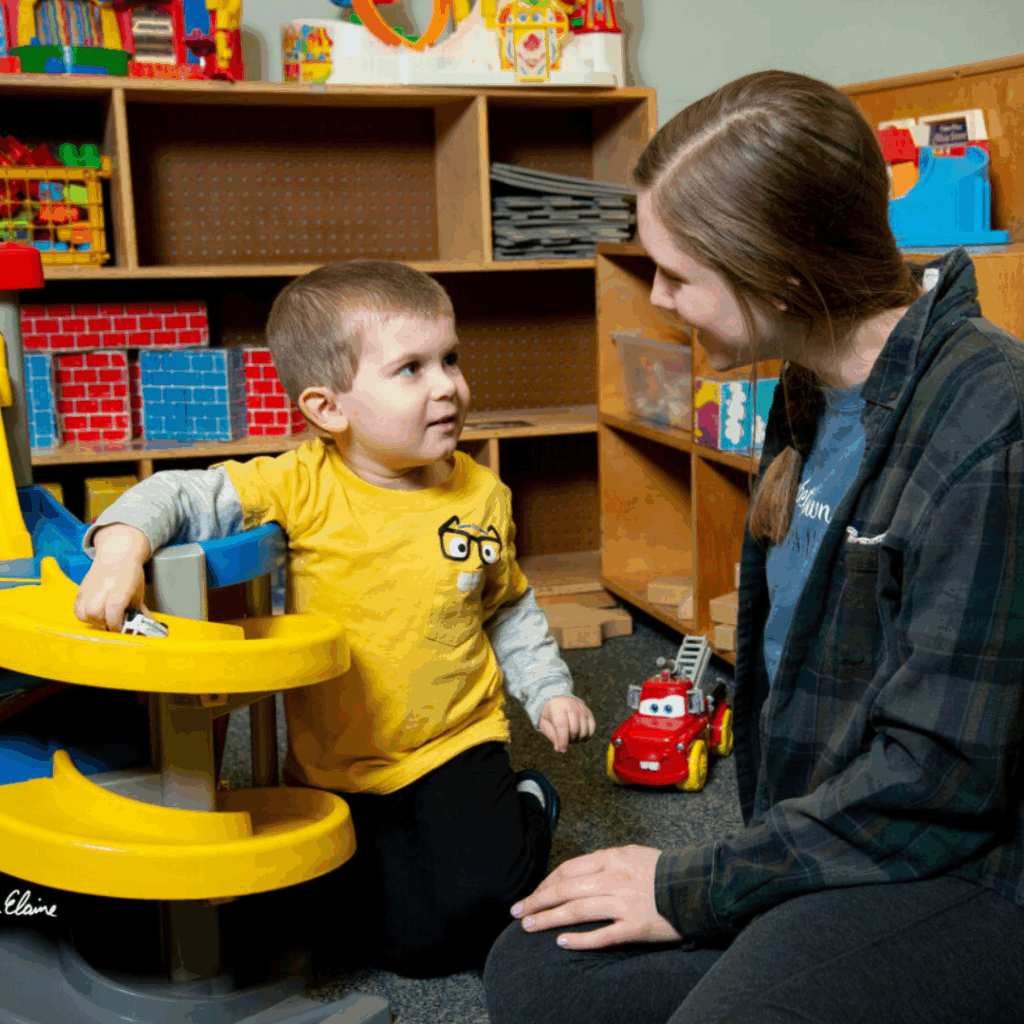Little boy playing cars with young woman