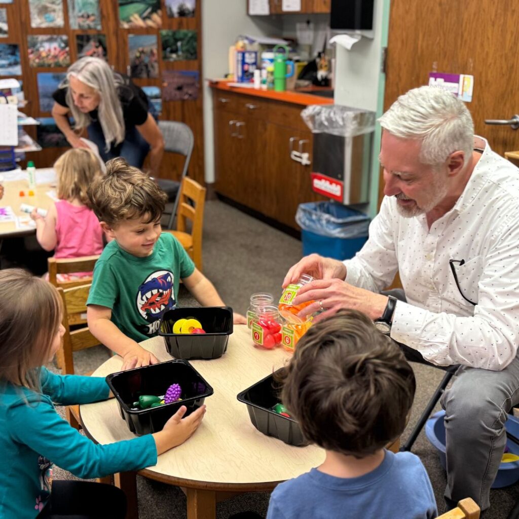 preschool students sitting around a table with their teacher