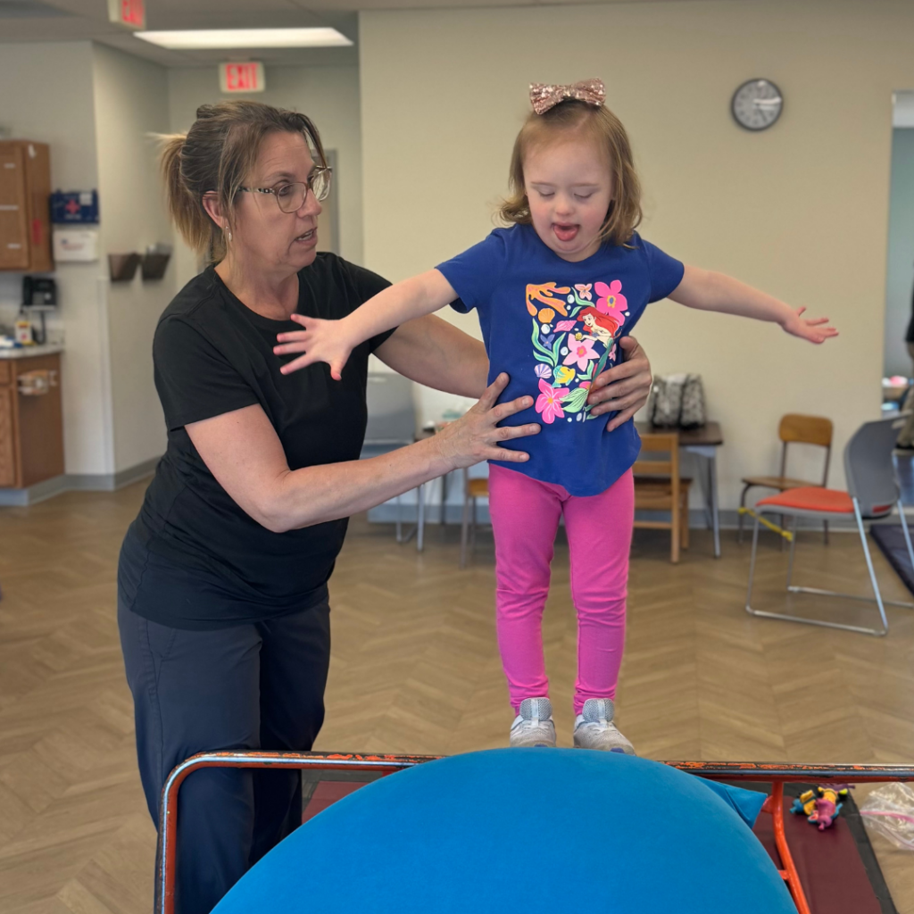 young girl getting ready to jump onto a therapy mat with therapist
