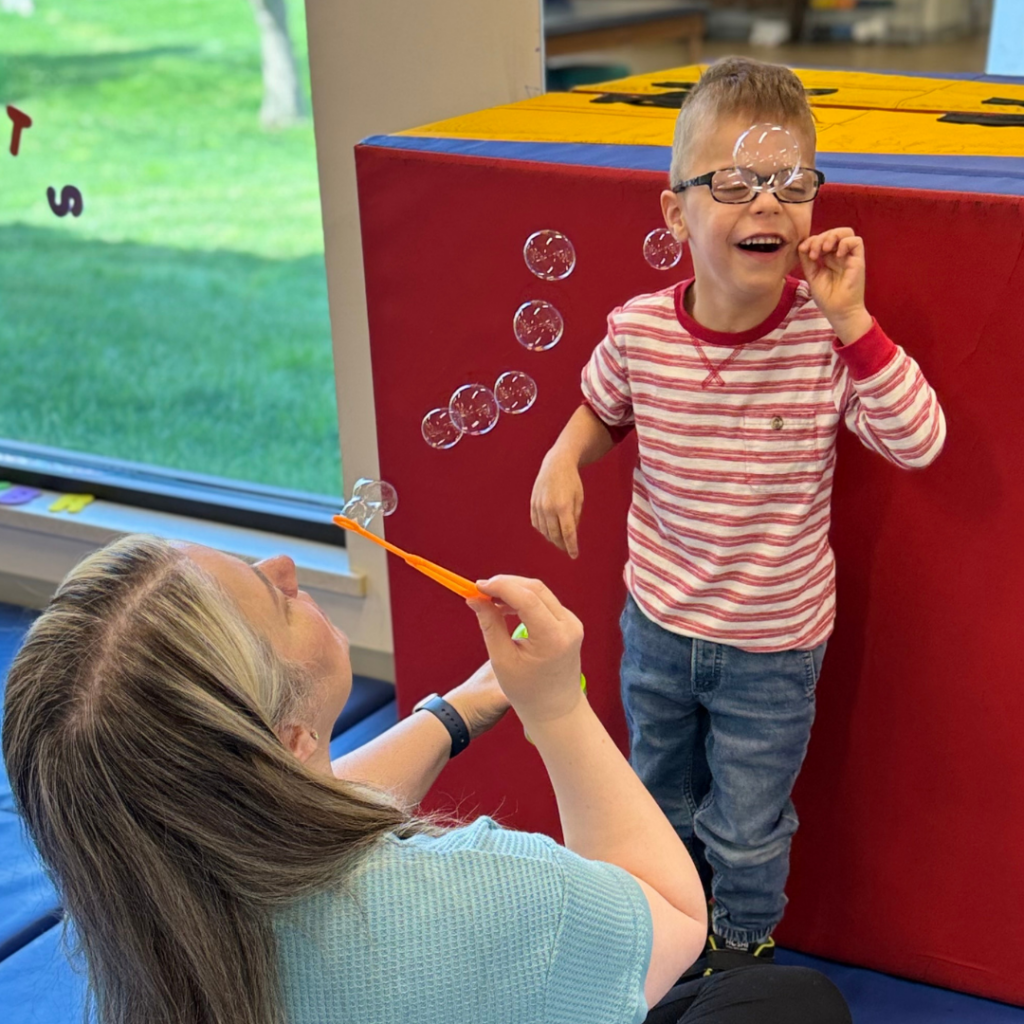 young boy with therapist blowing bubbles