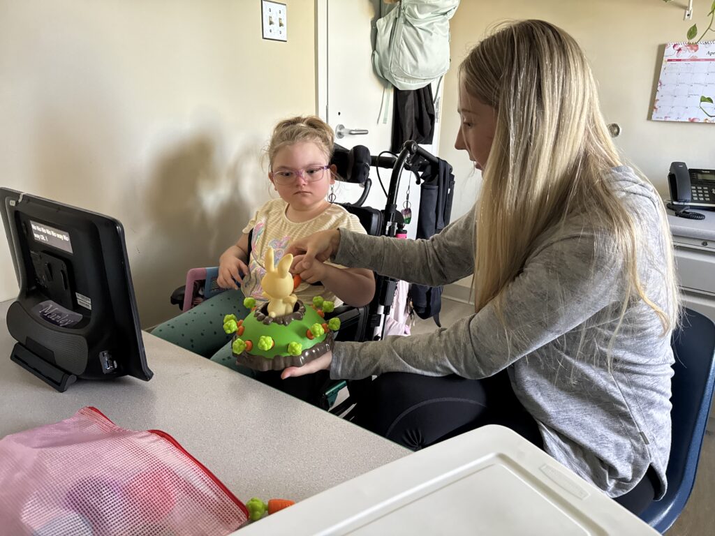 young girl in wheelchair playing a game with her therapist