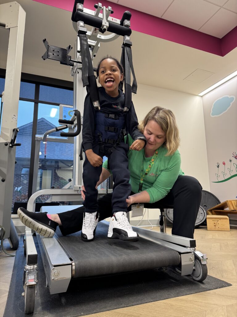 young boy in litegait harness with therapist