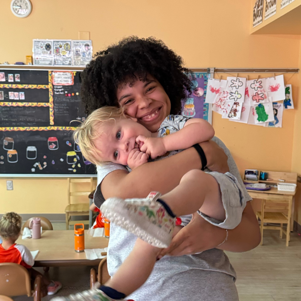 toddler being held by teacher