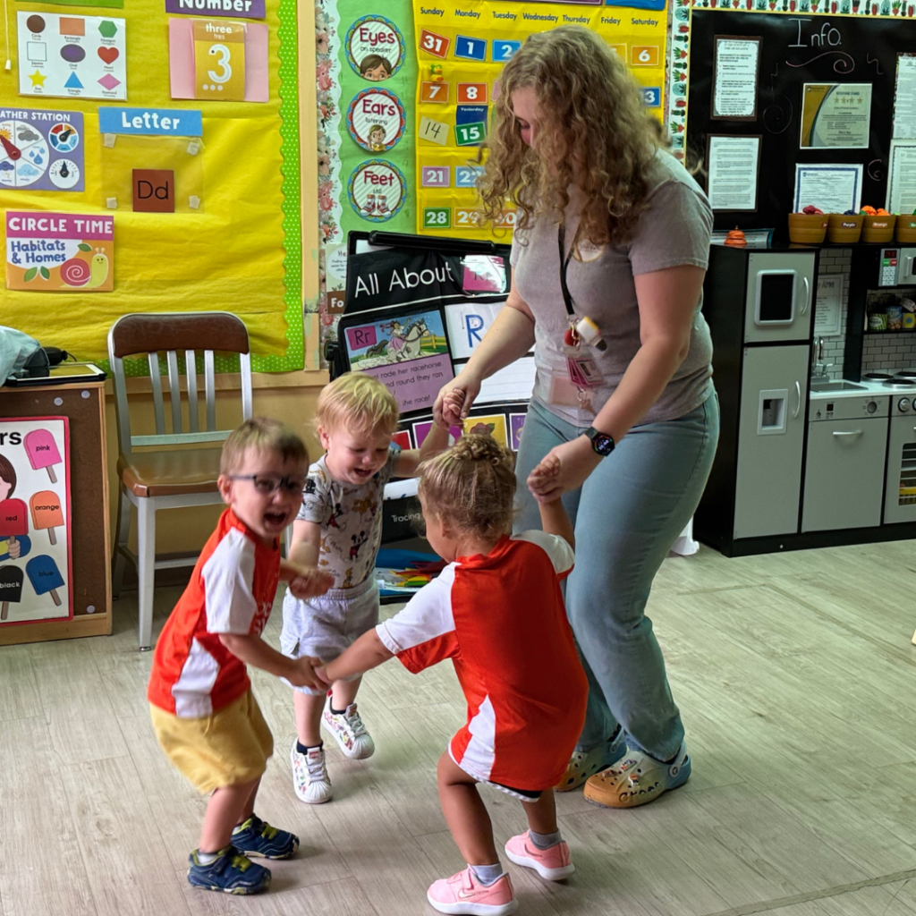 three toddlers dancing with teacher