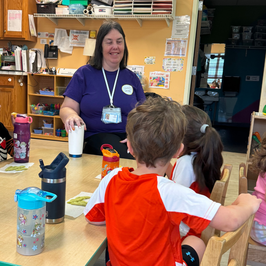 two students having snack time with their teacher