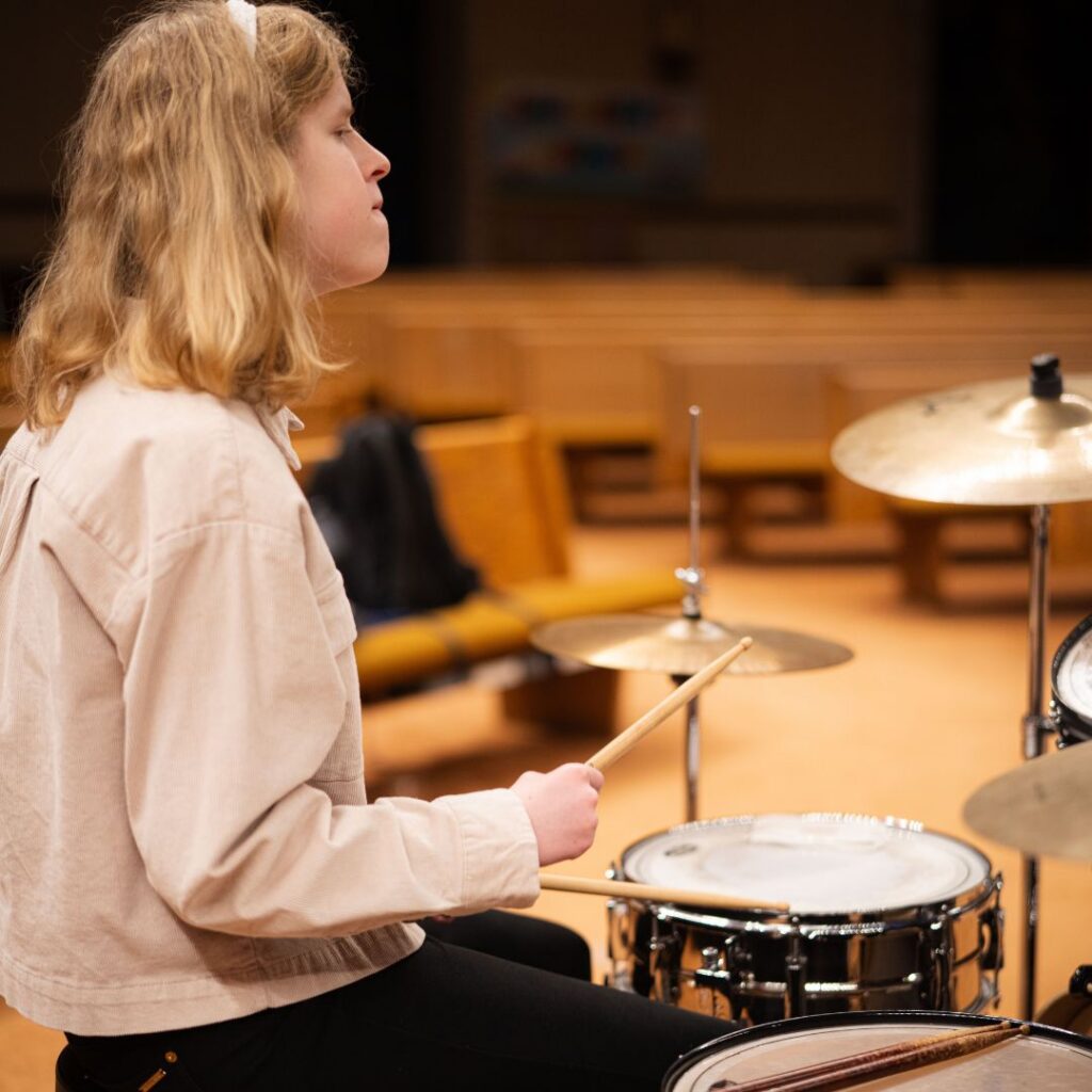 side profile of young woman playing the drums